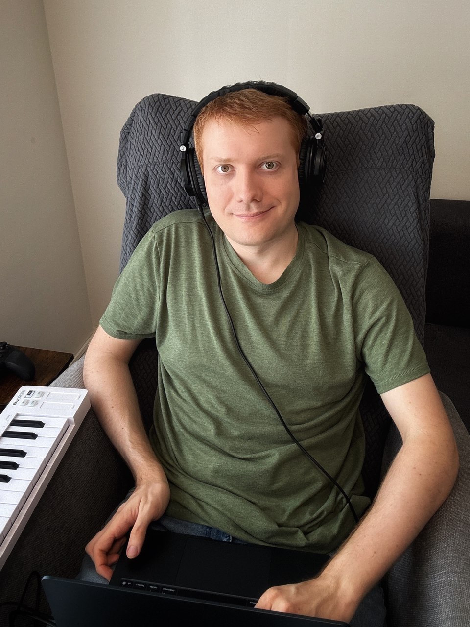 Dominik Witka working on a track with headphones, a MIDI keyboard and a laptop